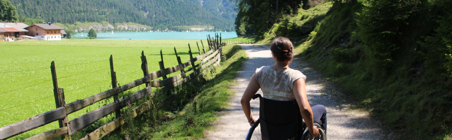Bild zeigt eine Frau im Rollstuhl am See