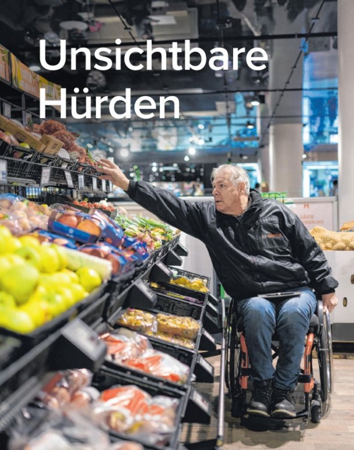 Bernold Dörrer im Rollstuhl in einer Einkaufssituation im Supermarkt - er erreicht die höher gelegenen Obst- und Gemüsesorten vom Rollstuhl aus nicht. 
